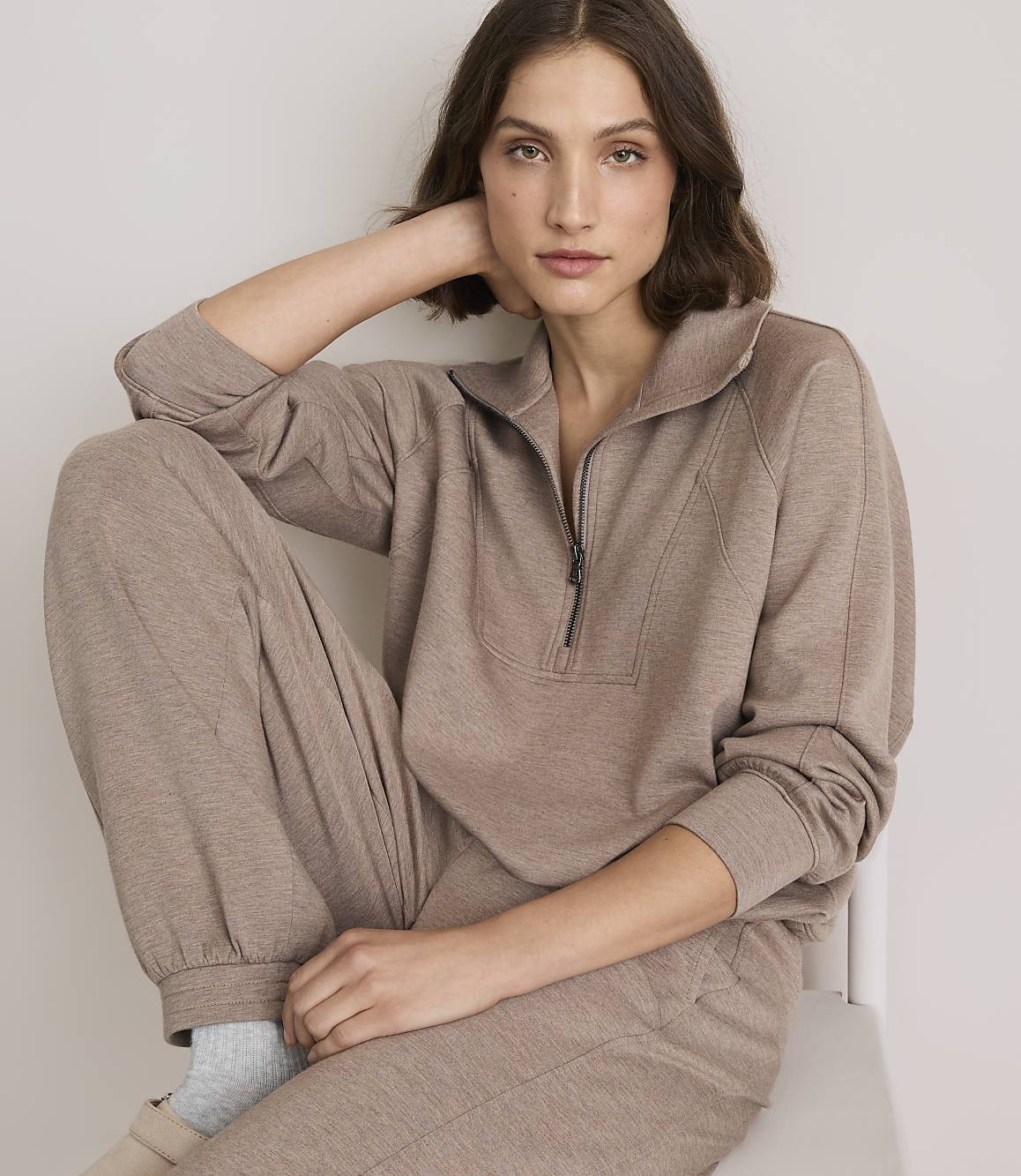 A woman in a brown loungewear set poses against a plain white background.