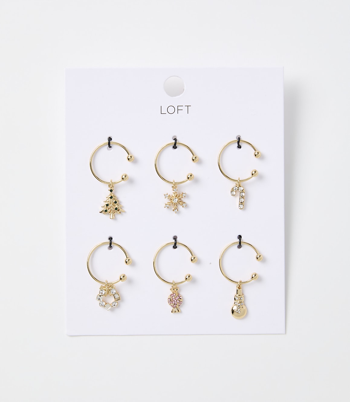 Six gold-toned hoop earrings with festive Christmas charms hang from a white card with the "LOFT" logo against a plain white background.
