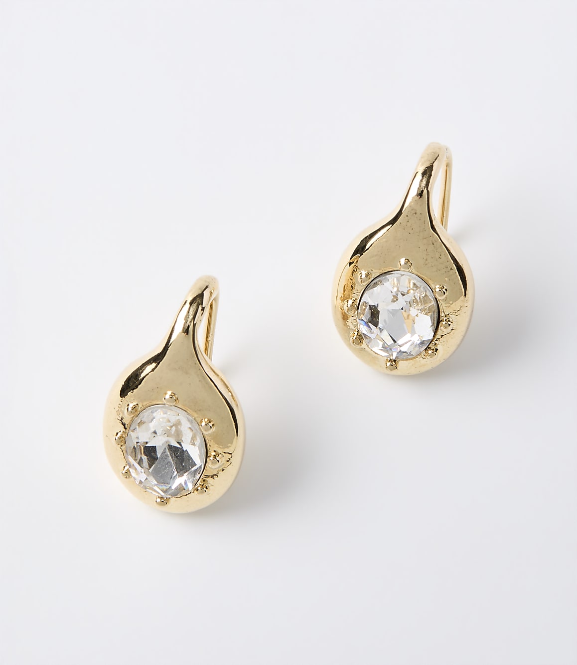 A pair of gold teardrop earrings with clear gemstones are displayed against a plain white background.