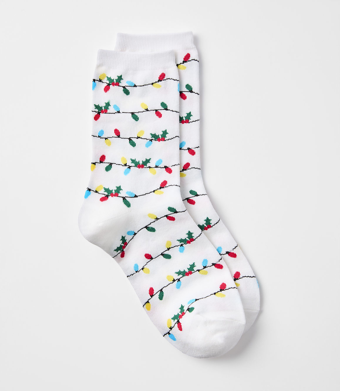 A pair of white socks with a pattern of colorful Christmas lights and holly adorns the foreground, set against a plain white background.