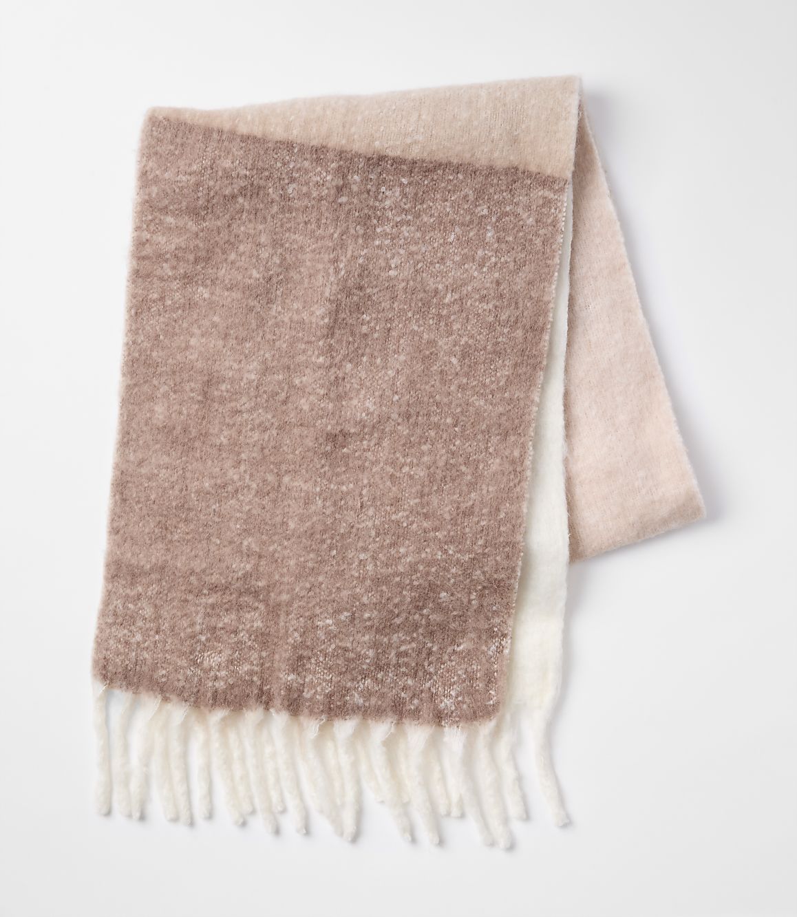 A soft, textured scarf with cream fringe lies folded against a plain white background.