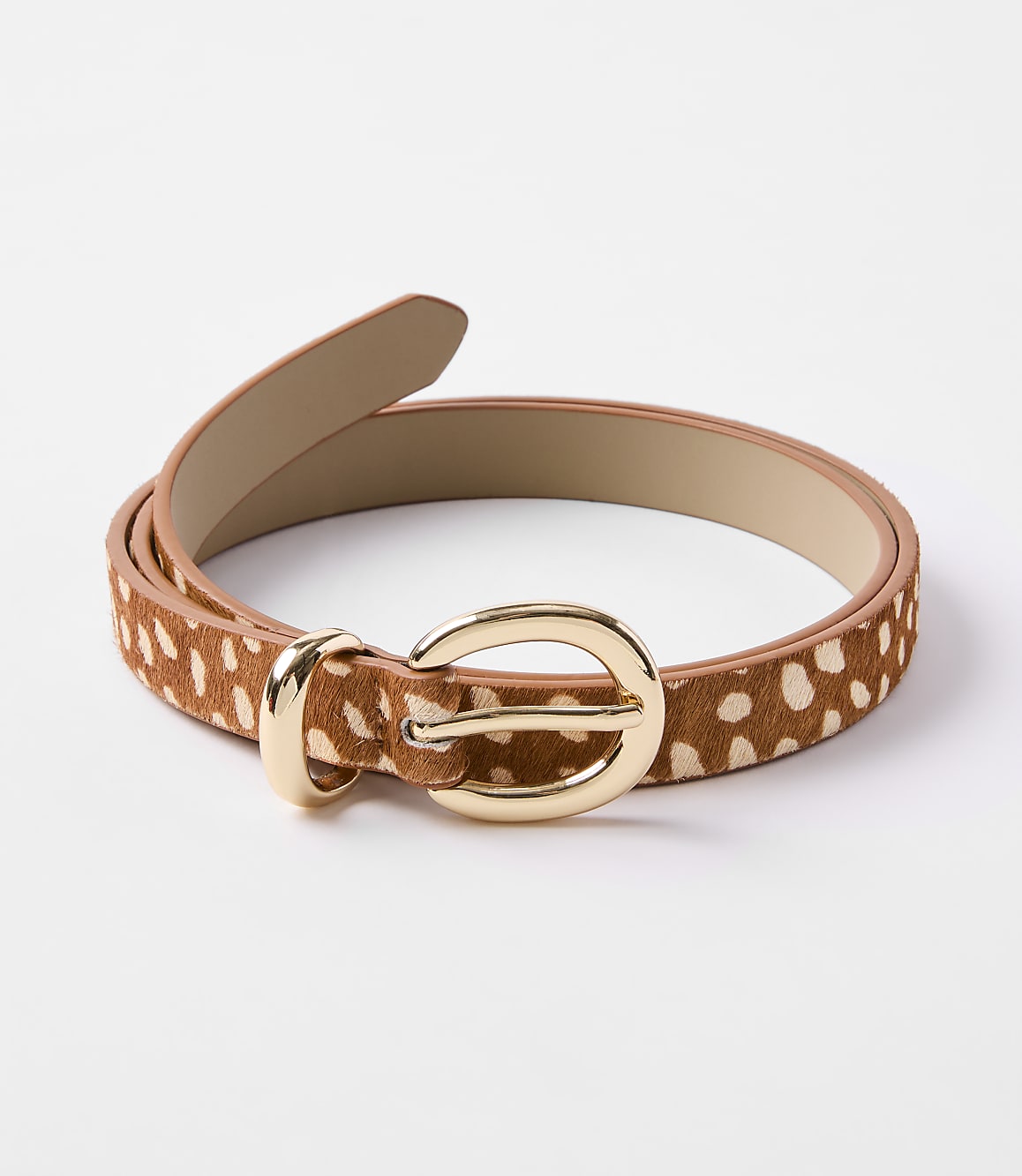 A brown and white spotted belt with a gold buckle lies on a plain white background.