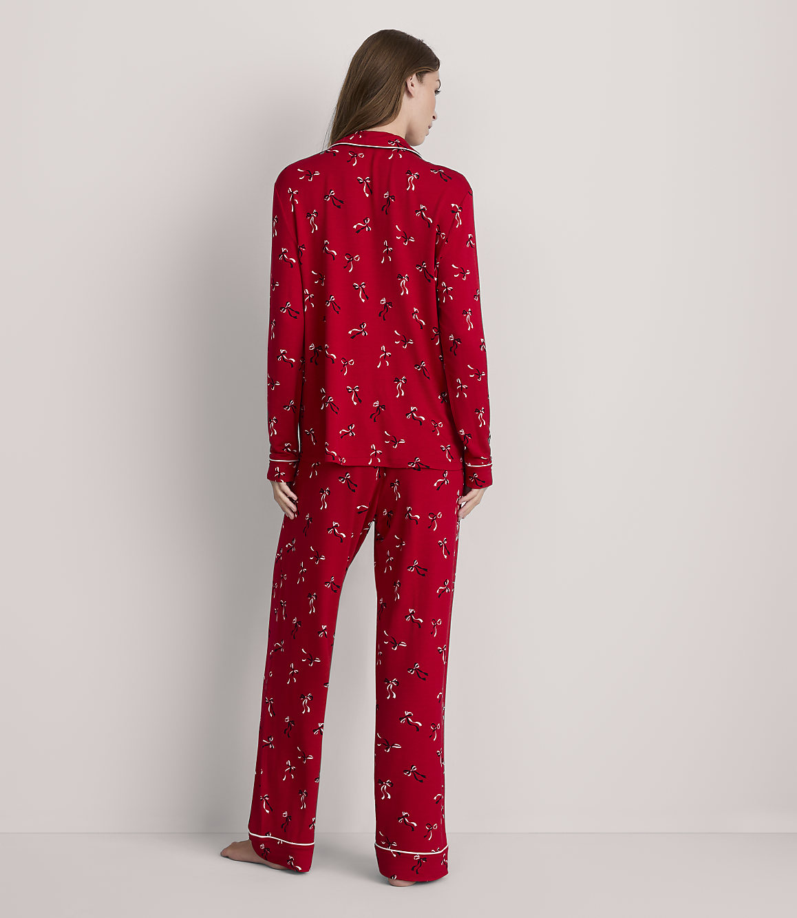A woman in red patterned pajamas stands against a plain white background.