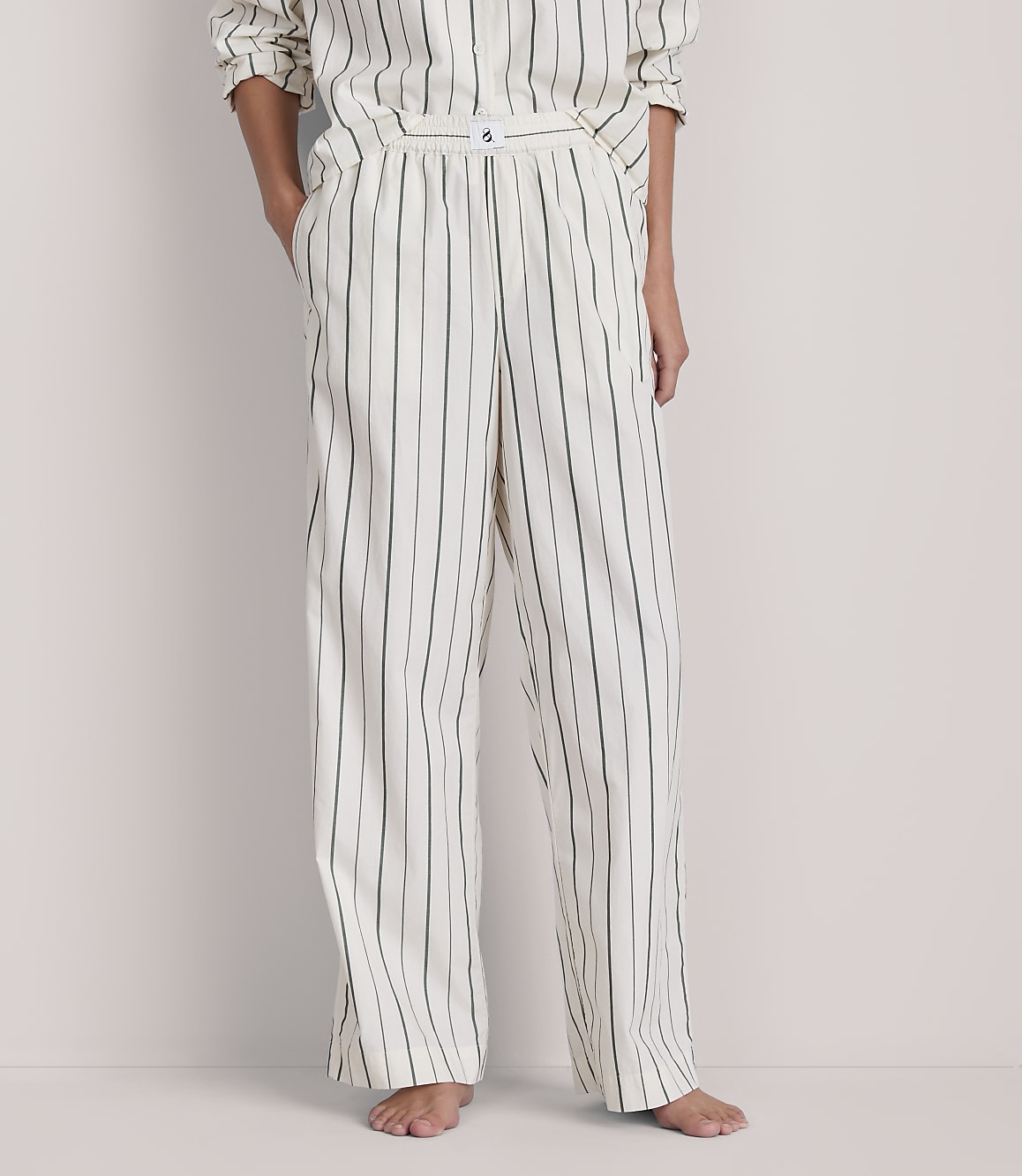 A person stands in striped pajamas against a plain background.