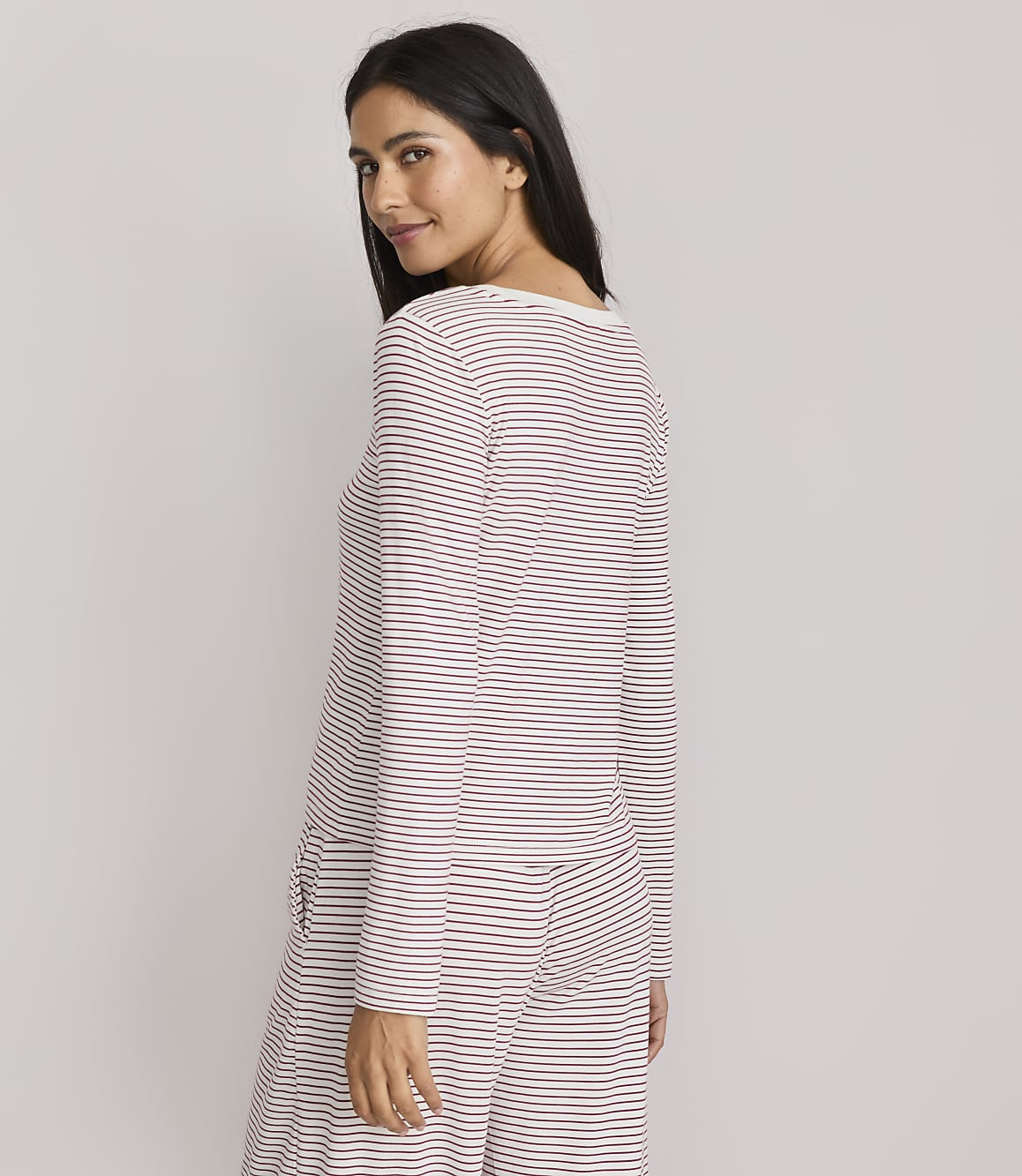 A woman in striped pajamas poses against a plain, light gray background.