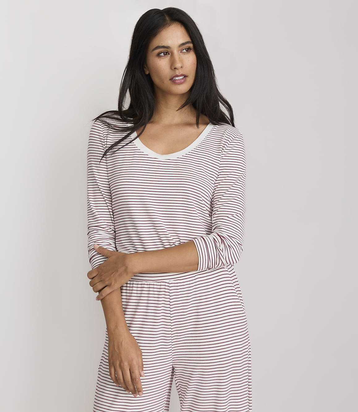 A woman in a striped pajama set stands against a plain white background.
