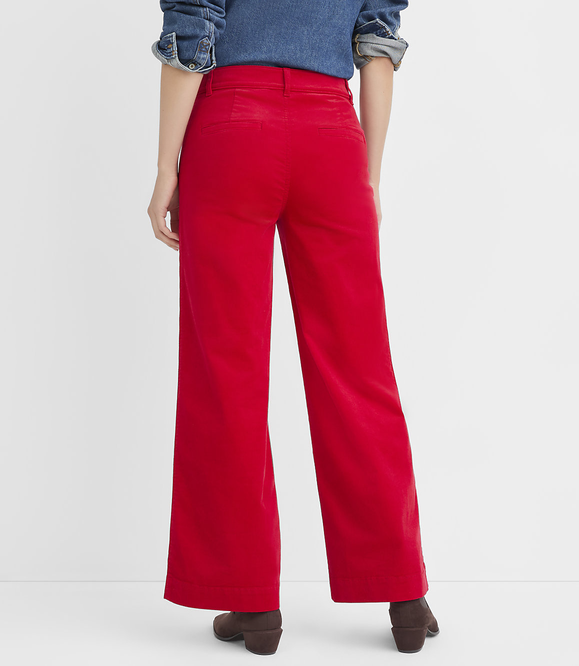 A person wearing bright red wide-leg pants and brown boots stands against a plain white background.