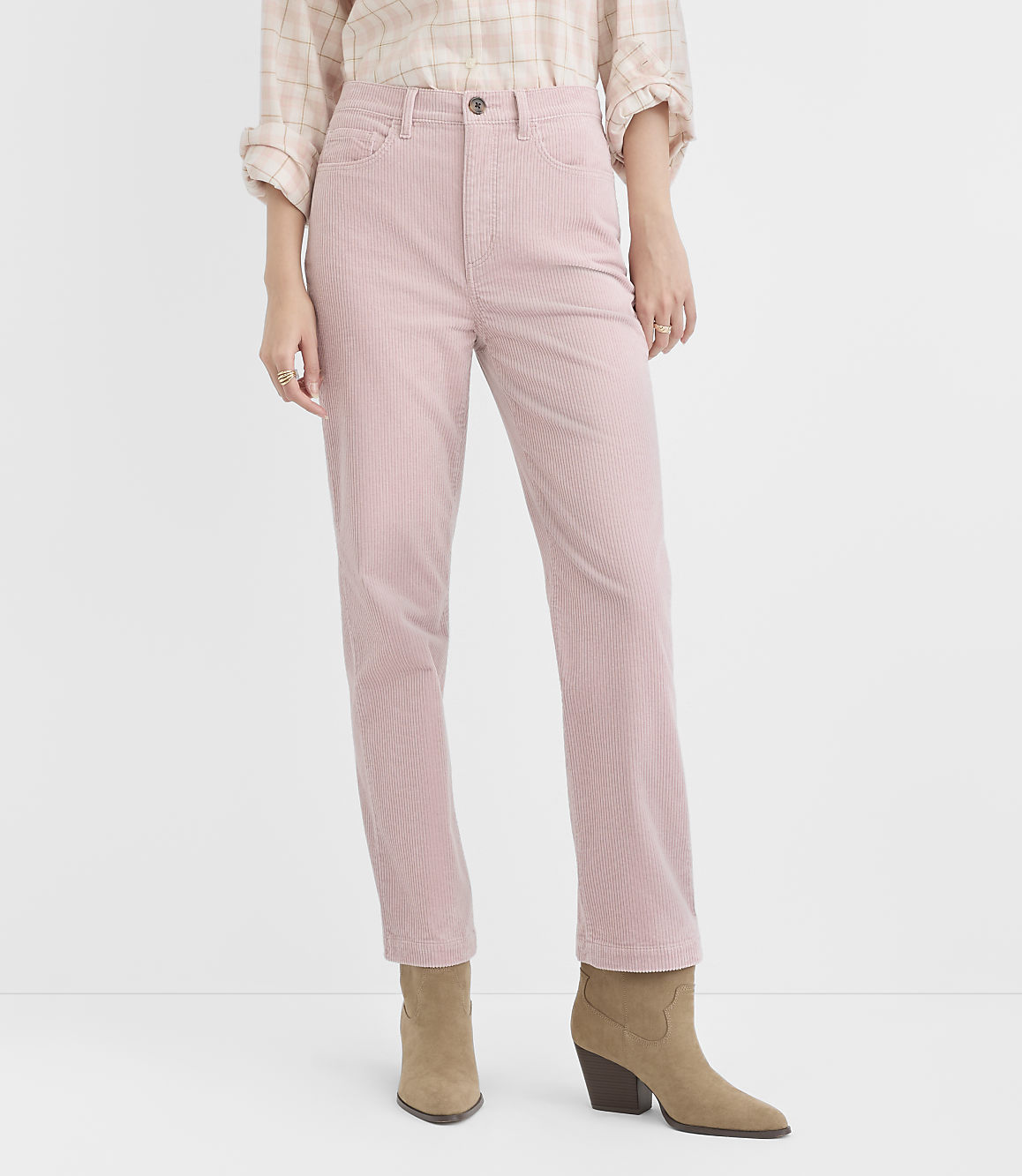 A person stands in light pink corduroy pants and tan ankle boots against a plain white background.
