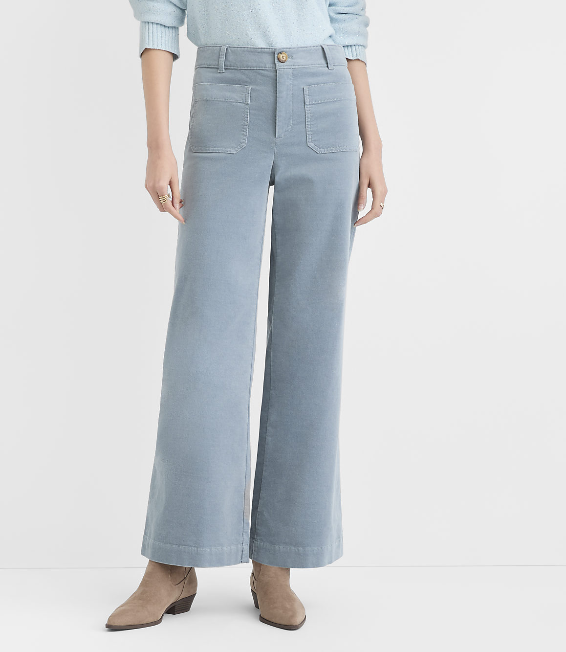 A person wearing light blue corduroy wide-leg pants and tan ankle boots stands against a plain white background.