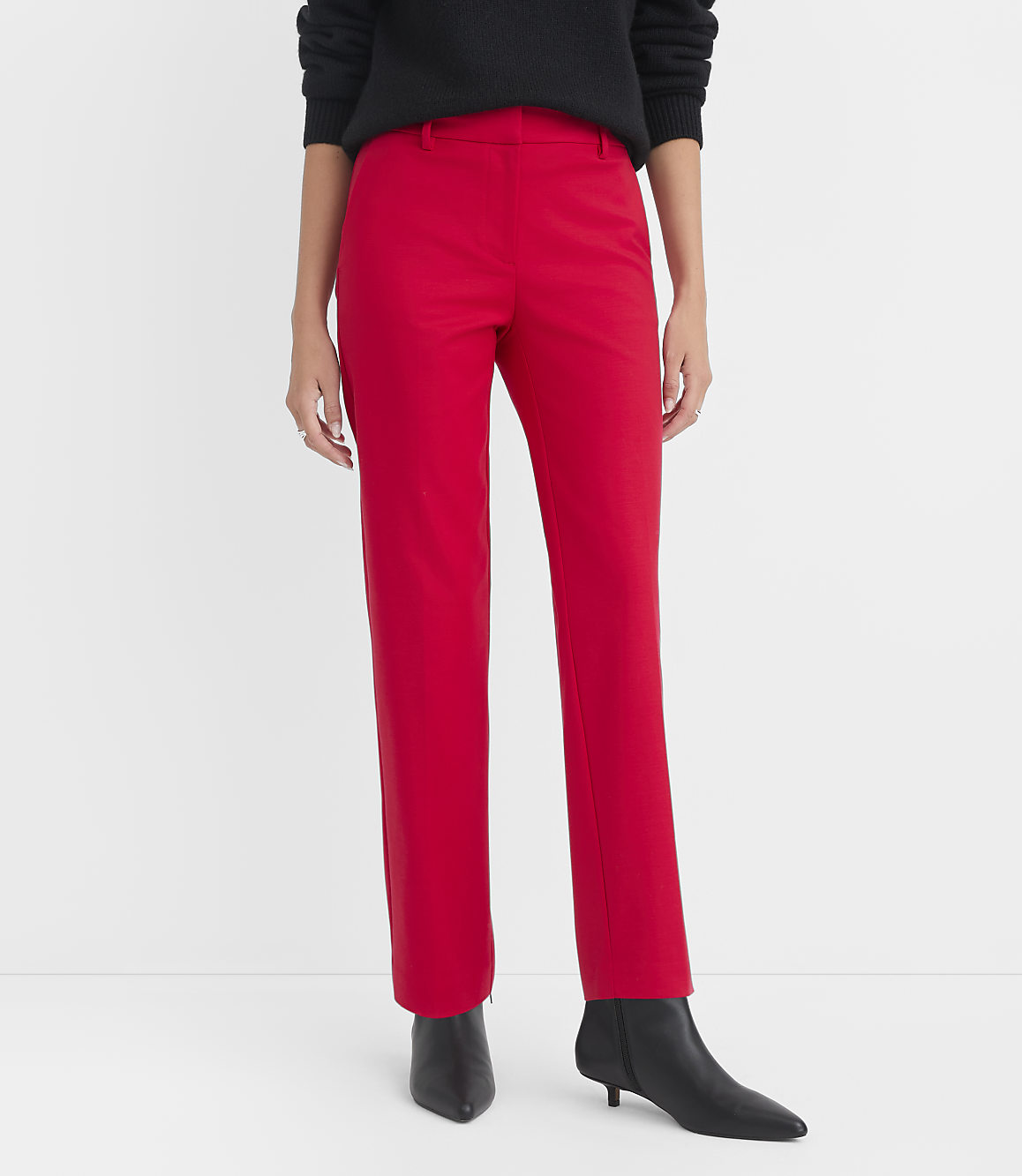 A person stands in bright red pants and black boots against a plain white background.