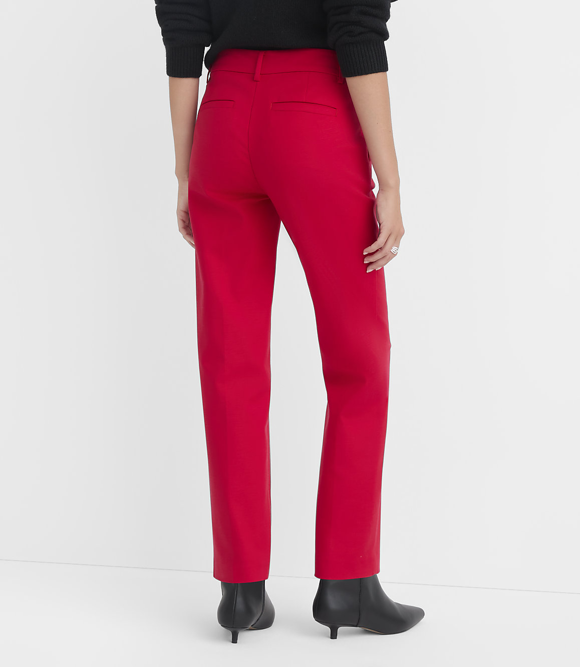 A person wearing red pants and black boots stands against a plain white background.