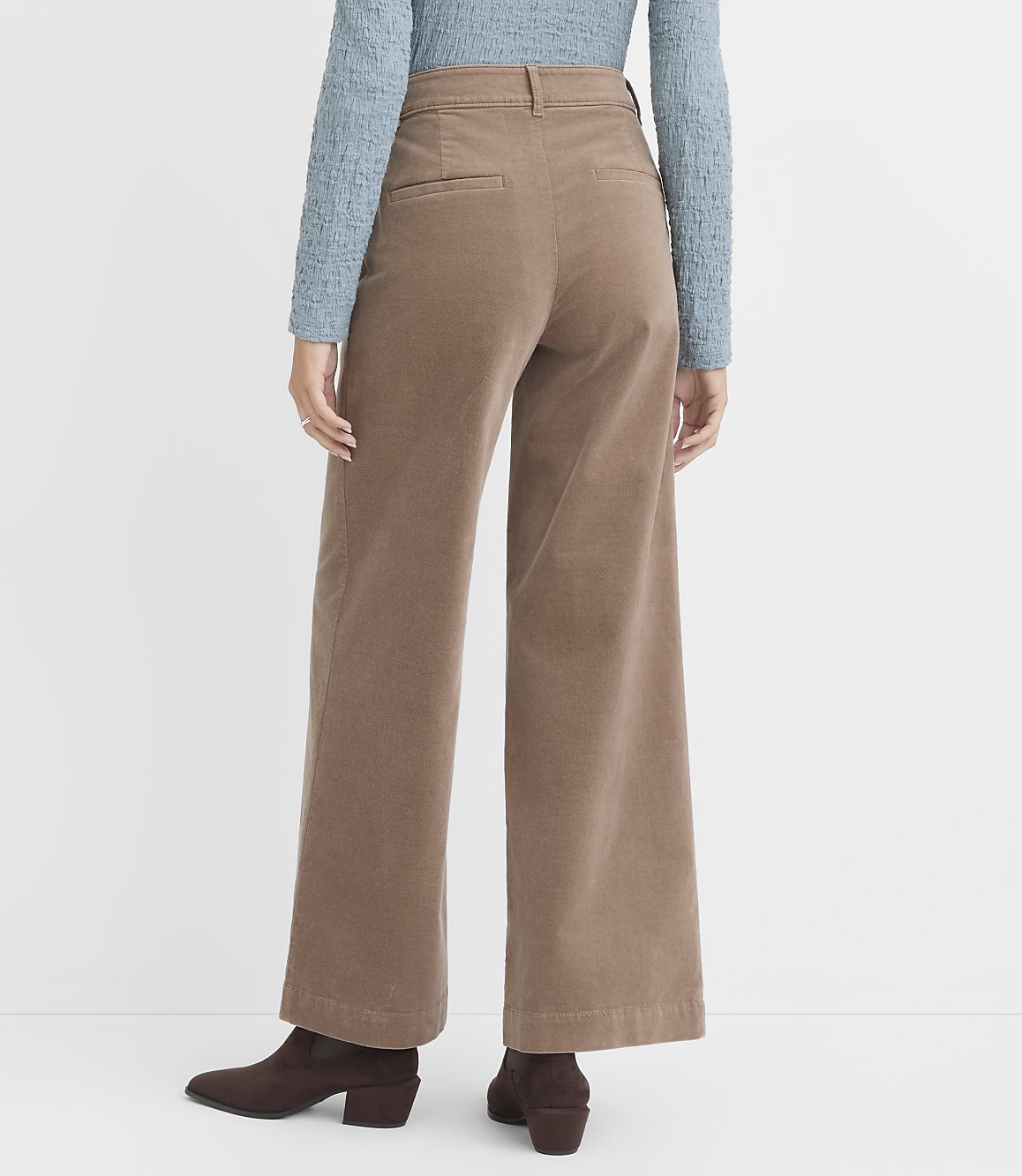 A person wearing wide-leg corduroy pants and brown boots stands against a plain white background.