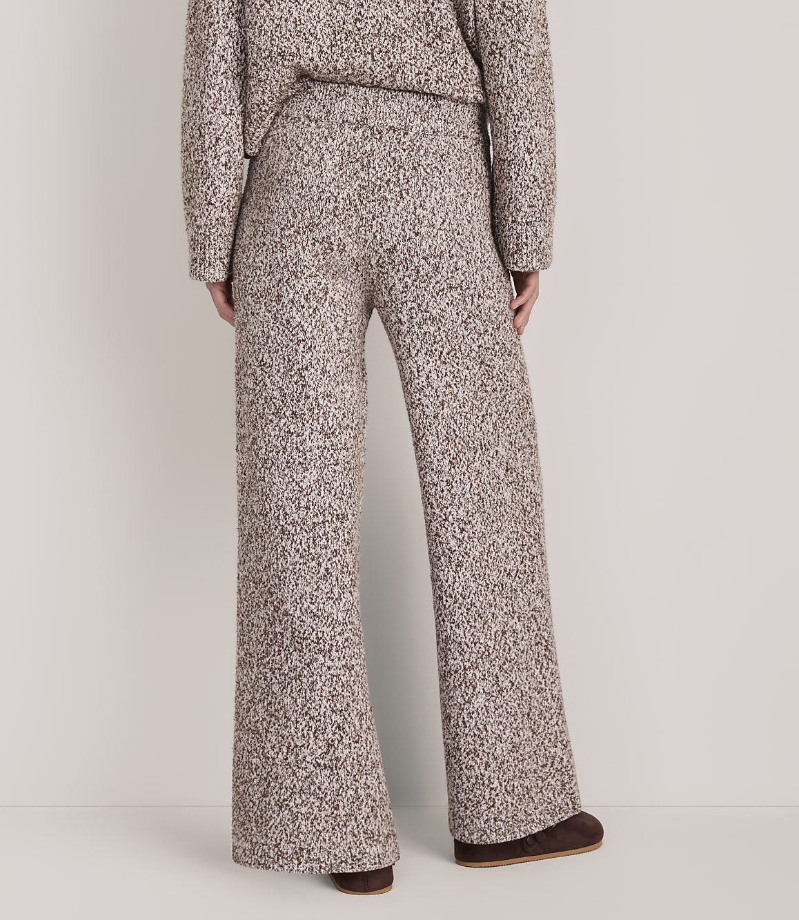 A person wears a matching brown and white textured knit sweater and wide-leg pants against a plain white background.