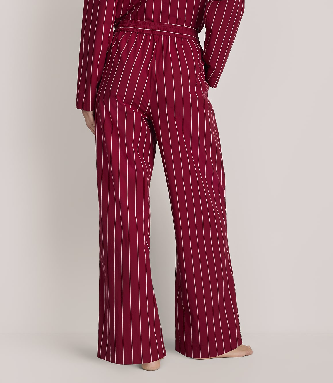 A person wears red and white striped wide-leg pajamas against a plain white background.