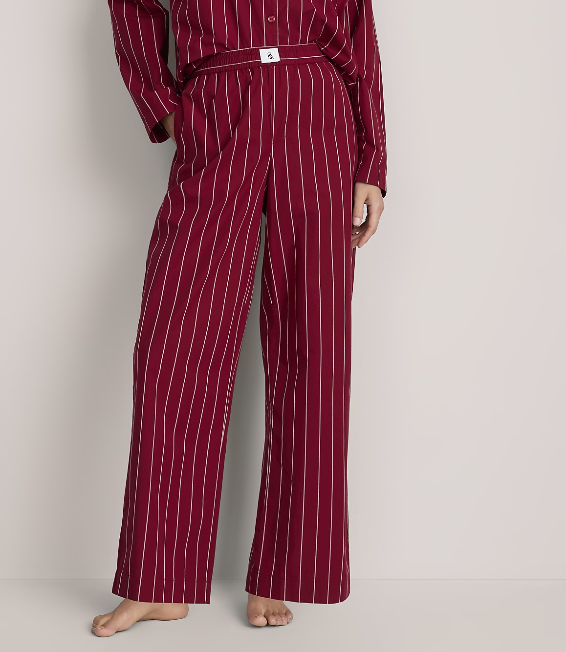 A person wears red and white striped pajamas against a plain, light-colored background.