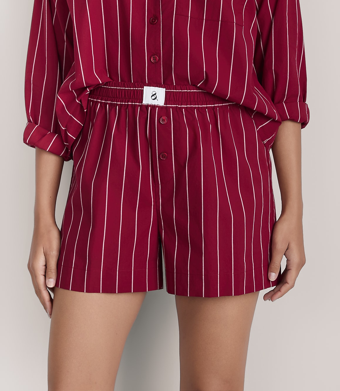 A person wears a red and white striped pajama set against a plain light gray background.
