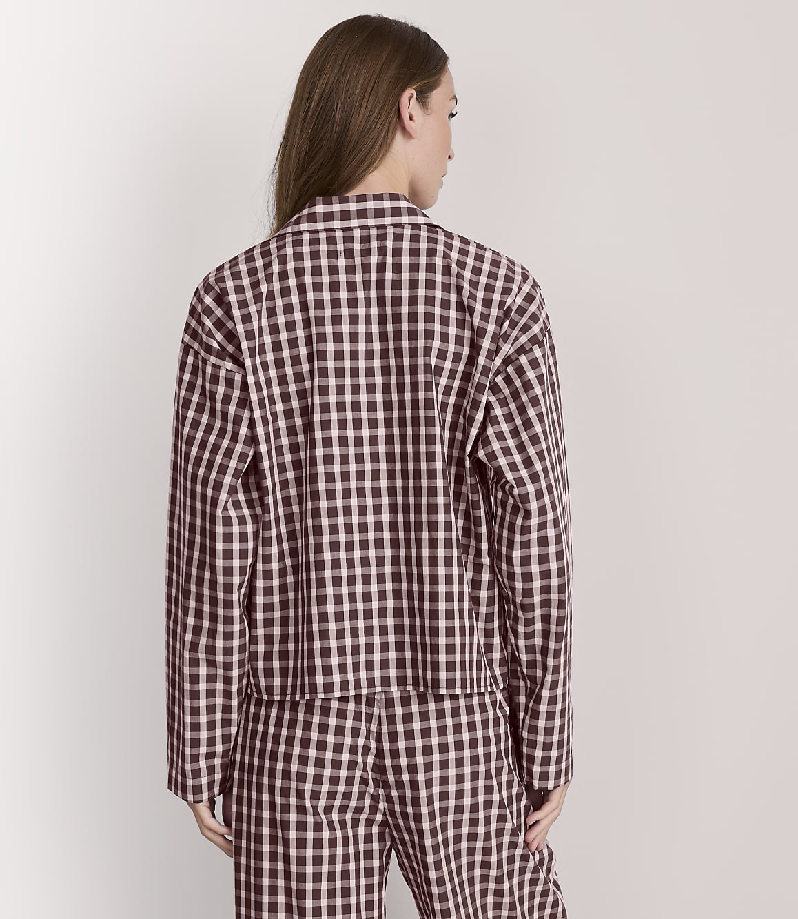 A woman in a black and white checkered jacket and pants stands against a plain white background.