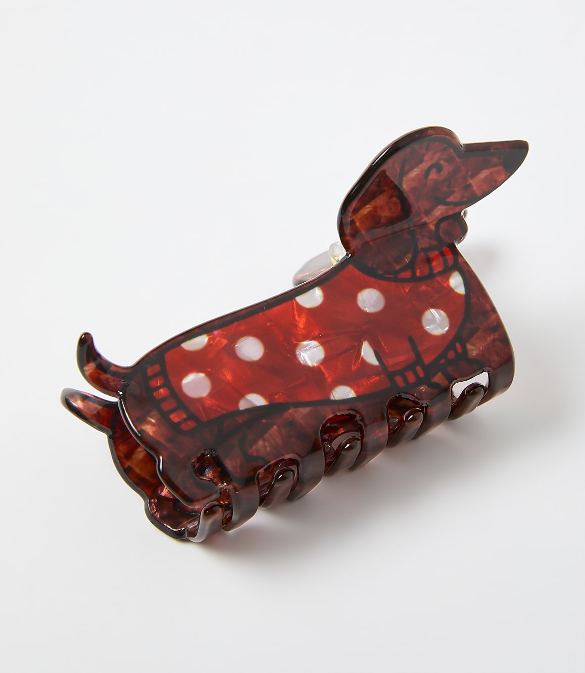 A red and white polka-dotted dachshund hair claw clip rests on a plain white background.