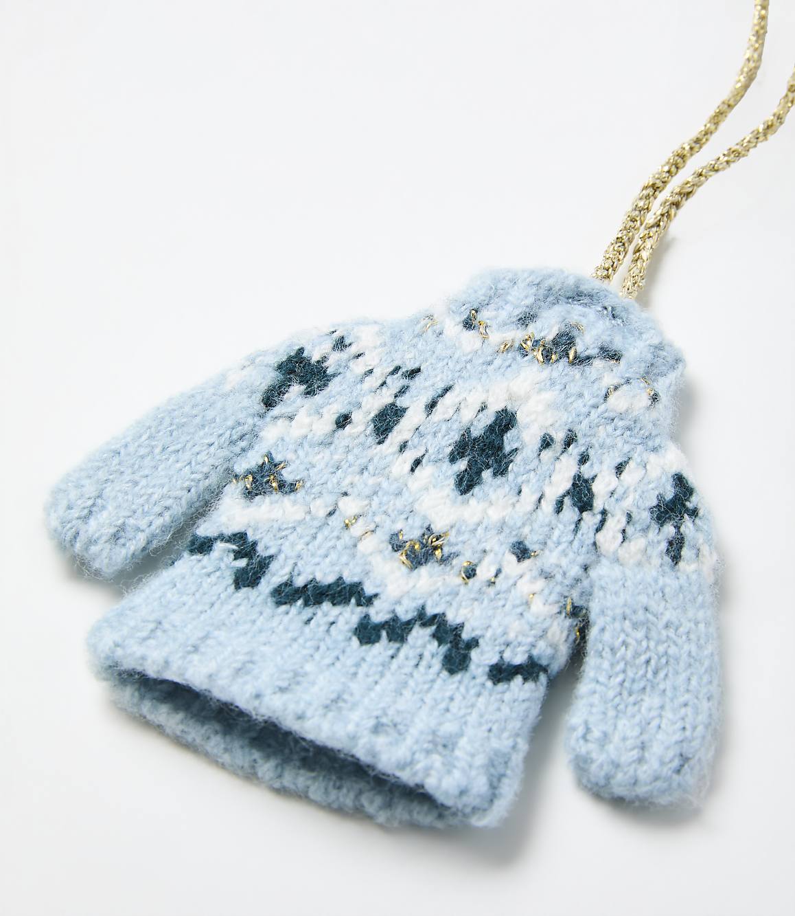 A small, knitted light blue mitten with white and dark blue patterns and a gold string sits against a plain white background.