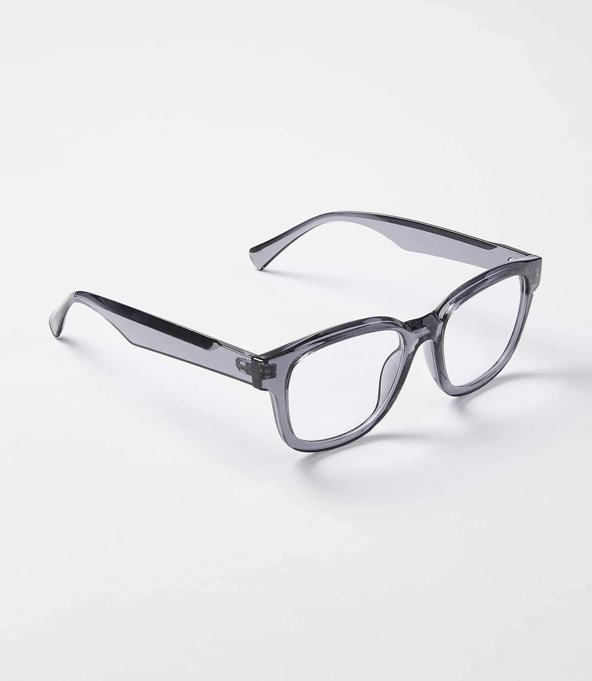 A pair of translucent grey glasses rests on a plain, light-colored surface.