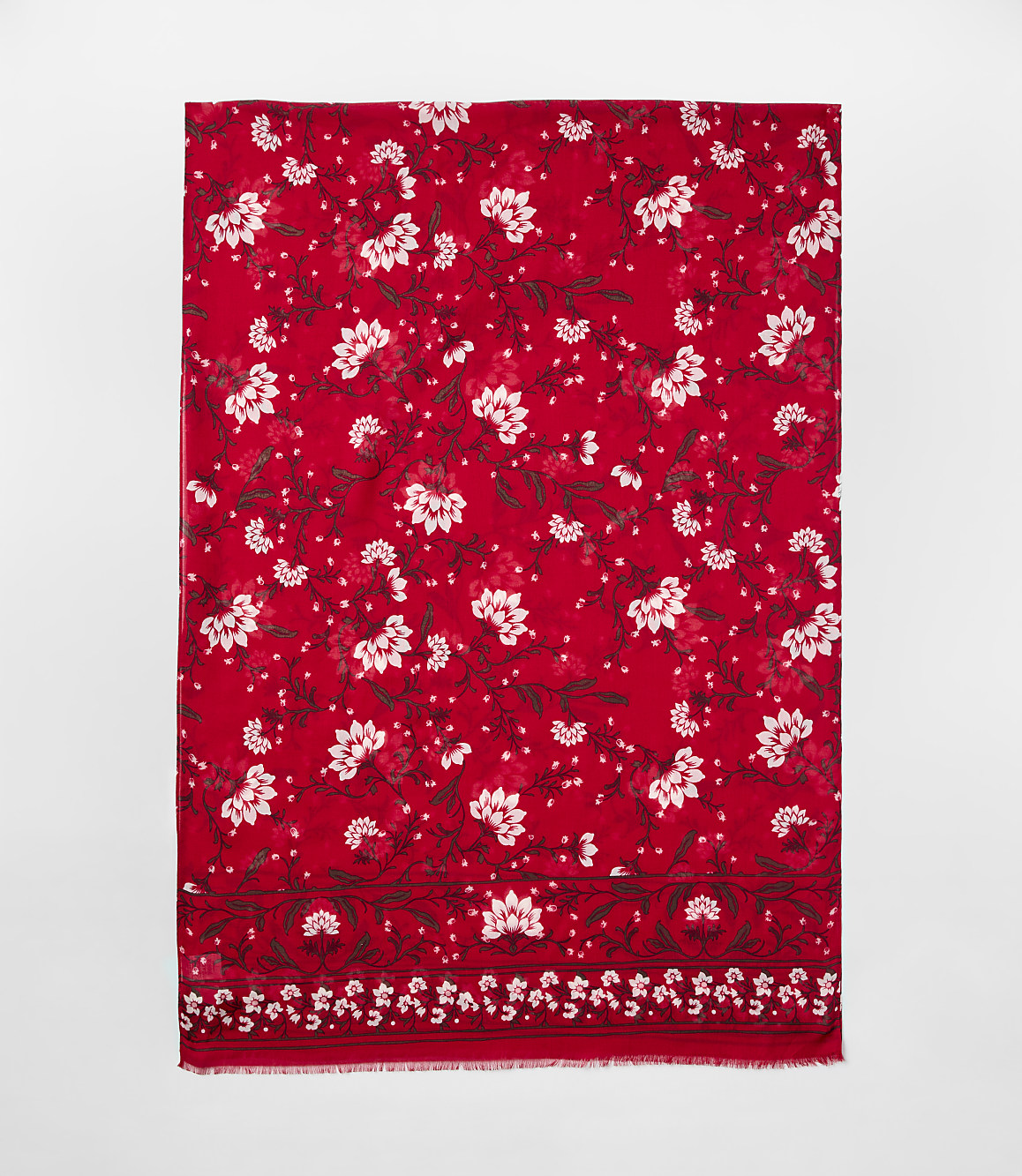A red scarf with white floral patterns is centered against a plain light gray background.