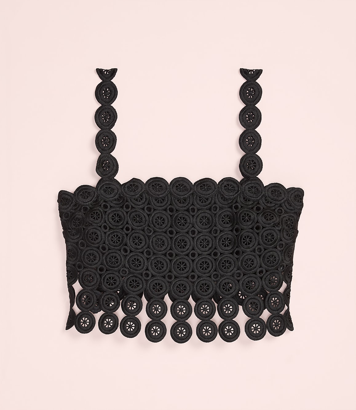 A black lace crop top with circular patterns is centered against a plain light pink background.