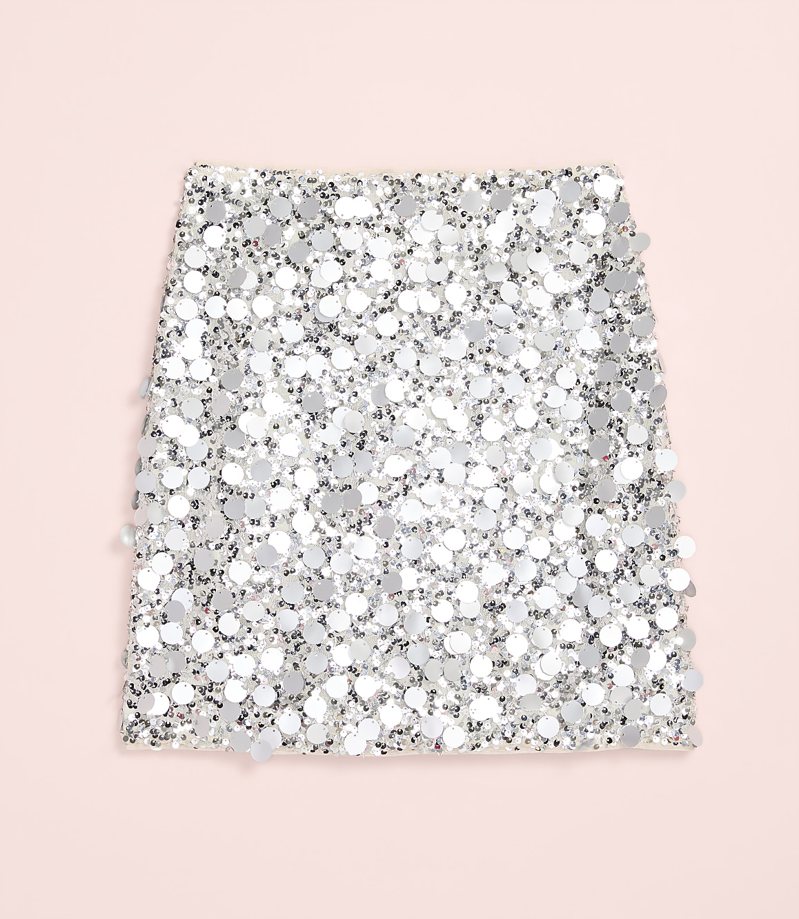 A shimmering silver sequined fabric piece rests on a solid light pink background.