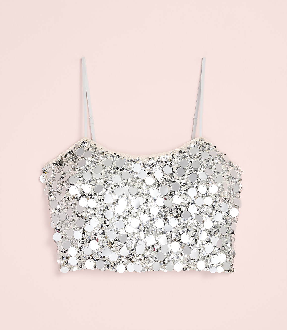 A silver sequined crop top with thin straps is centered against a solid light pink background.