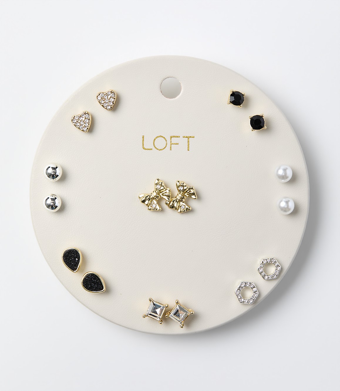 Various pairs of stud earrings are arranged on a circular white LOFT display card against a plain white background.