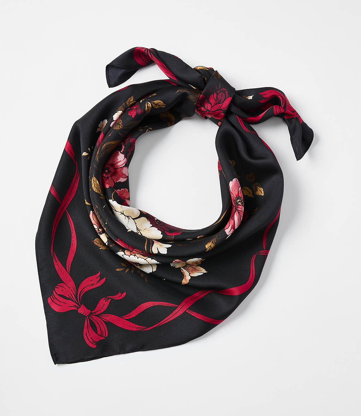A black floral scarf with red and white blossoms is tied in a knot against a plain white background.
