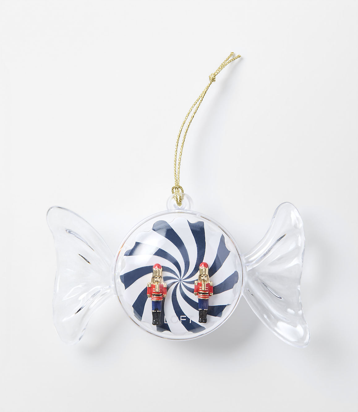 A clear candy-shaped ornament containing two small nutcracker figures against a blue and white swirl background, set against a plain white surface.