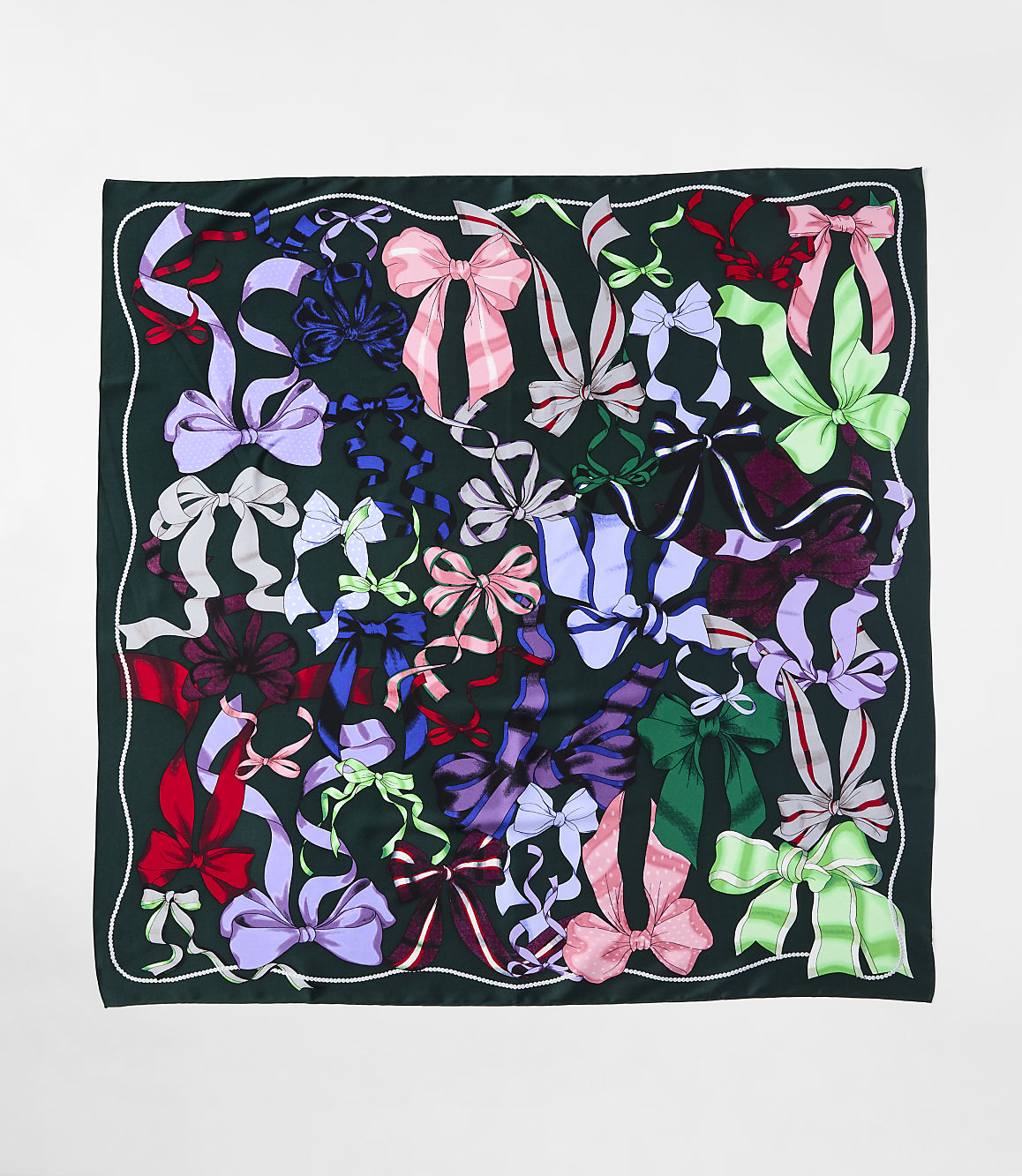 A variety of colorful ribbons and bows are scattered across a dark green fabric background.