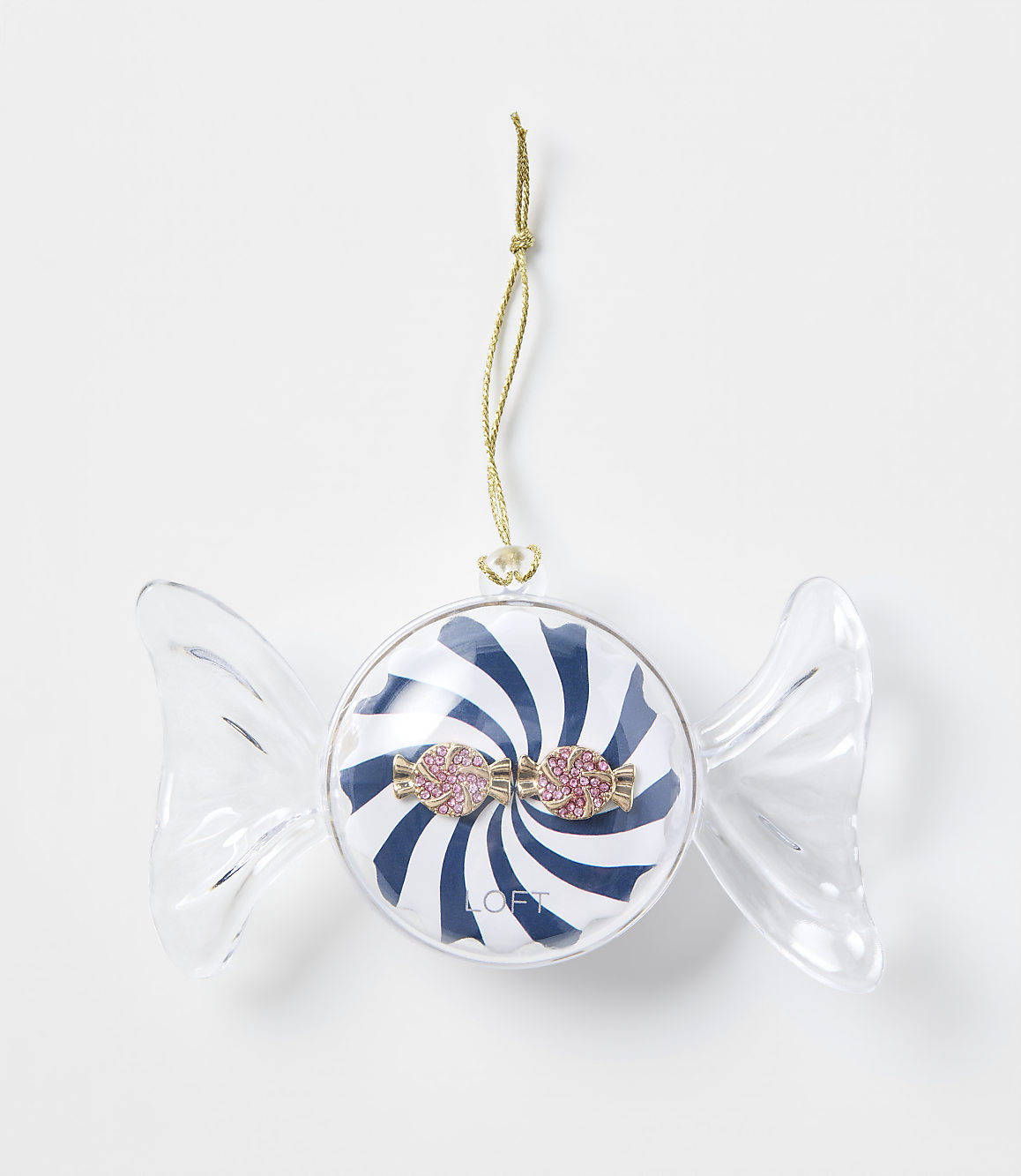 A blue and white striped candy ornament with pink glittery accents hangs by a gold string against a plain white background.