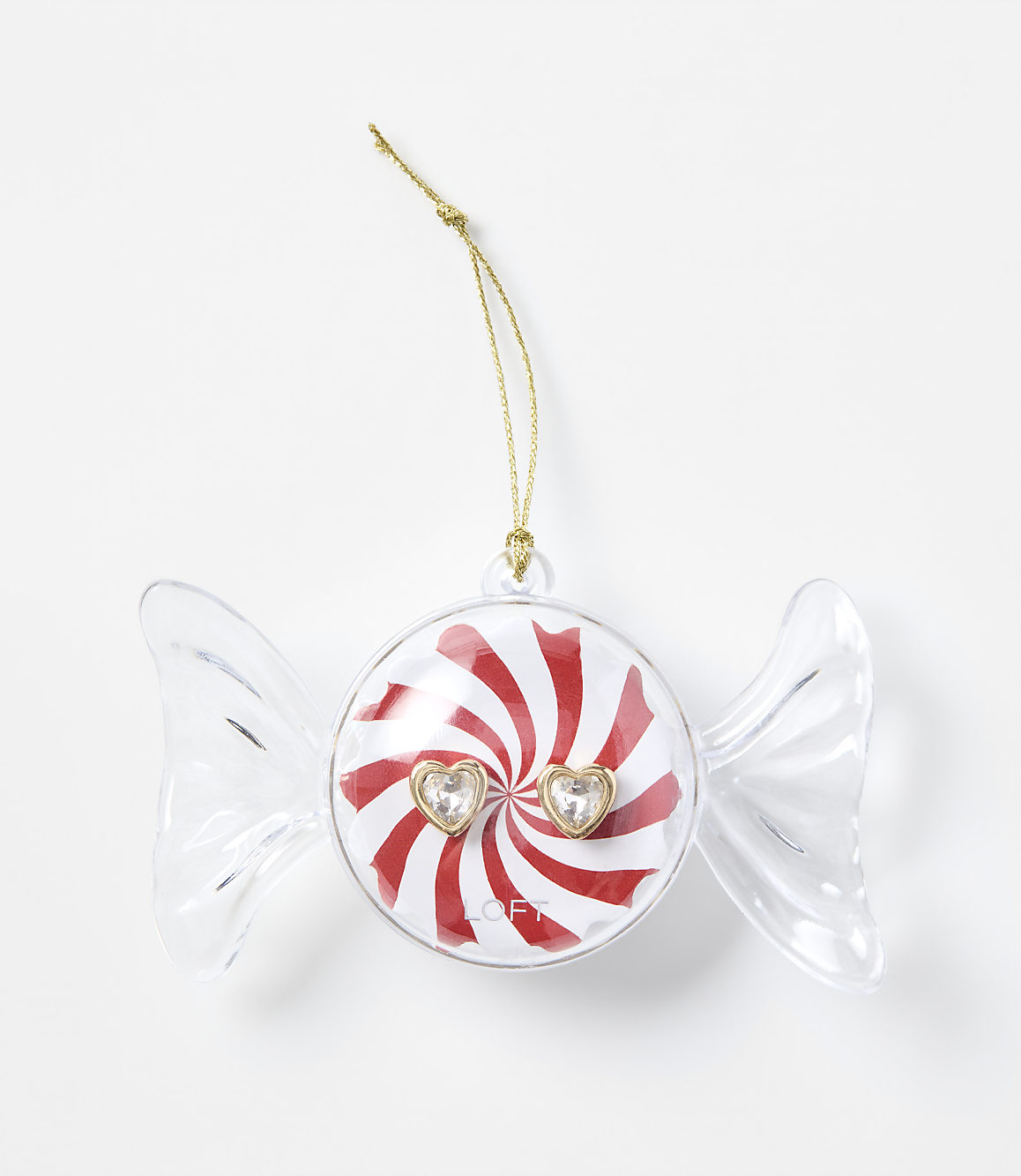 A clear candy-shaped ornament with a red and white peppermint center and two heart-shaped gems sits against a plain white background.