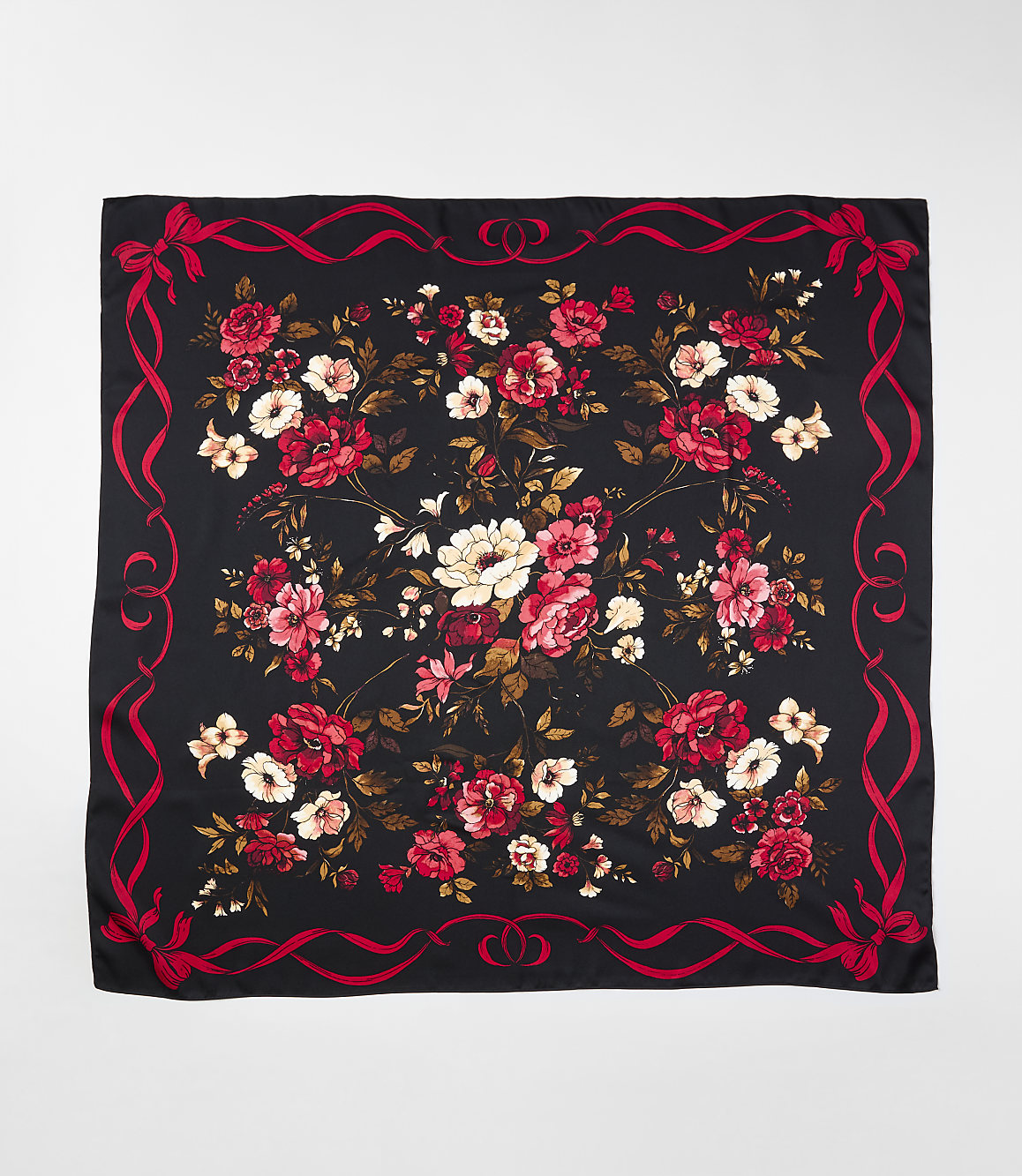 A black square scarf featuring a vibrant red and white floral pattern in the center, framed by a red ribbon border, set against a plain light gray background.