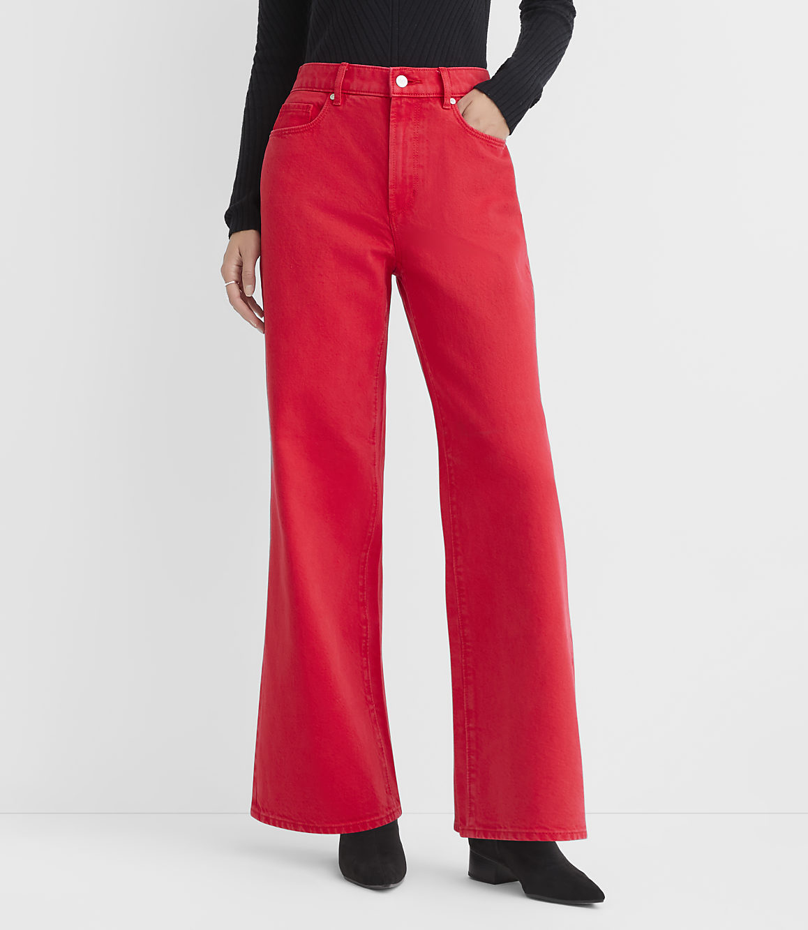A person wearing bright red flared jeans and black boots stands against a plain white background.