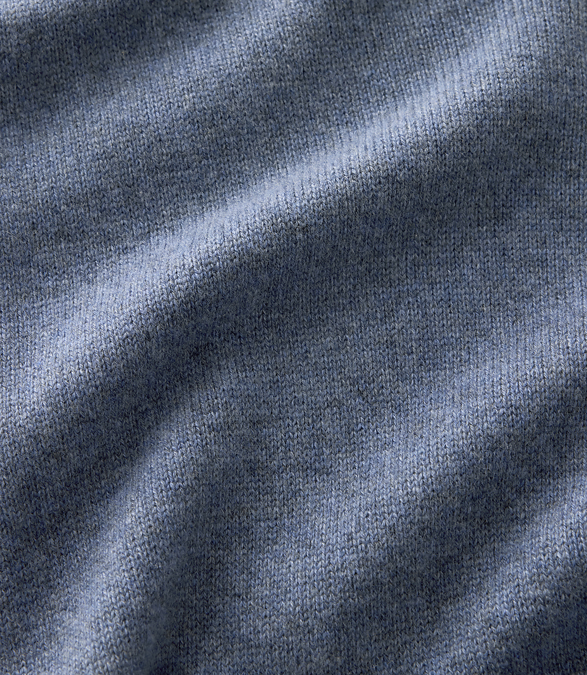 Blue knitted fabric with soft folds in the foreground and a consistent textured weave throughout the background.