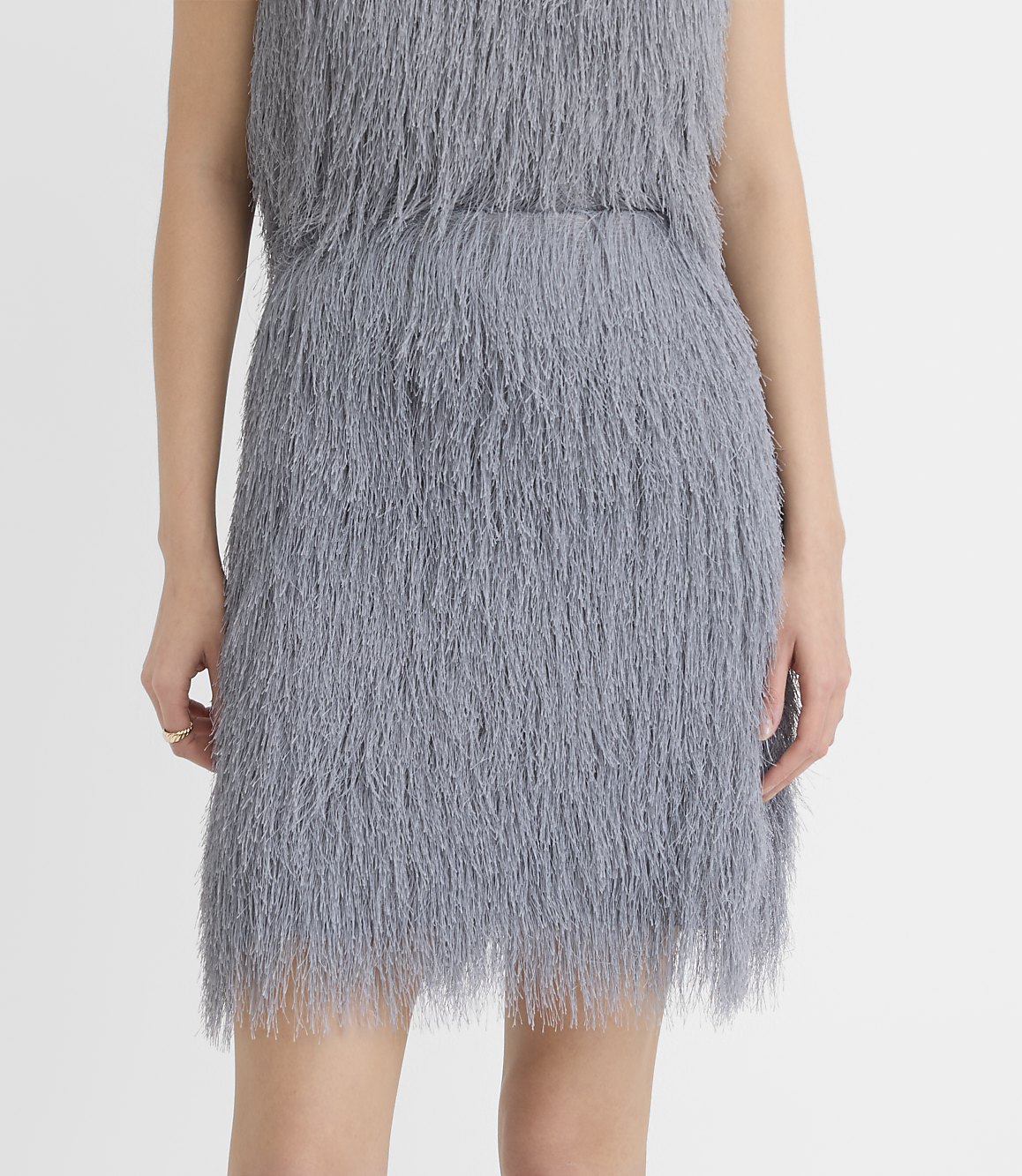 A person wears a grey shaggy faux-fur dress against a plain white background.
