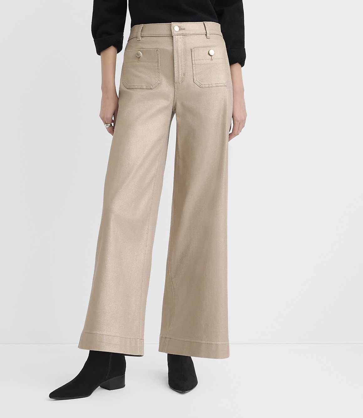 A person wears a black top, wide-leg beige trousers, and black ankle boots against a plain white background.