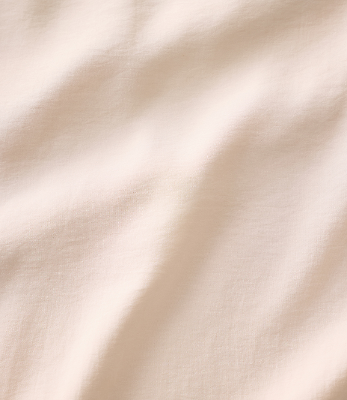 Soft, cream-colored fabric with gentle folds and ripples fills the entire frame.