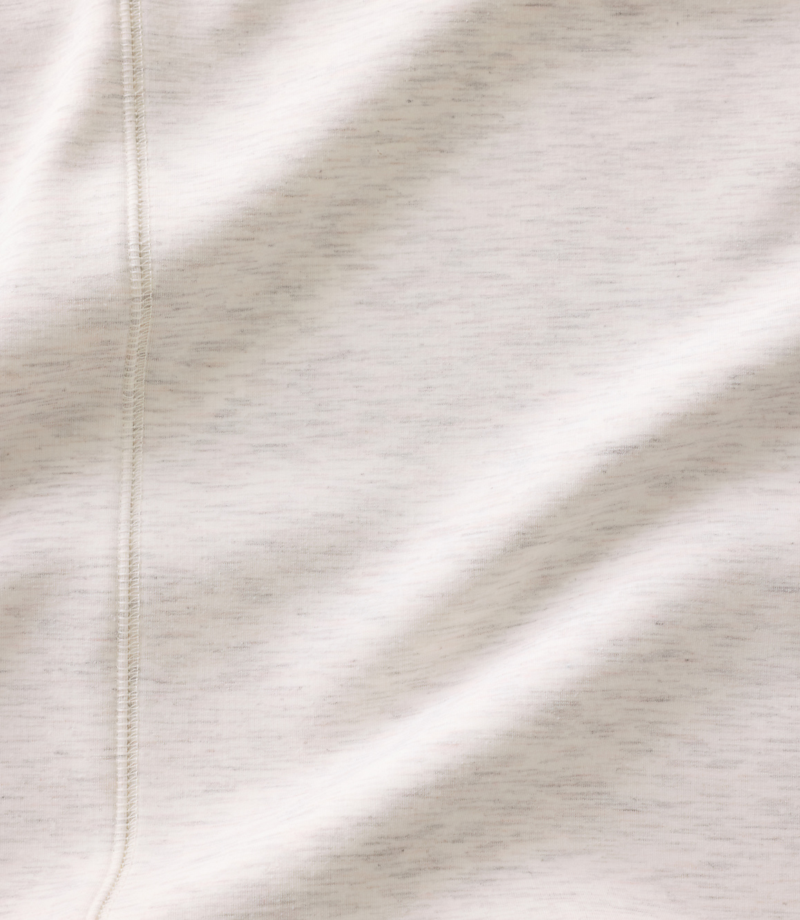 A close-up of a white fabric with a vertical seam in the foreground and soft folds across the background.
