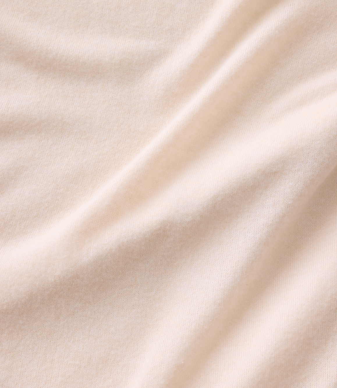 Soft, cream-colored fabric with gentle folds in the foreground and a smooth, consistent texture in the background.