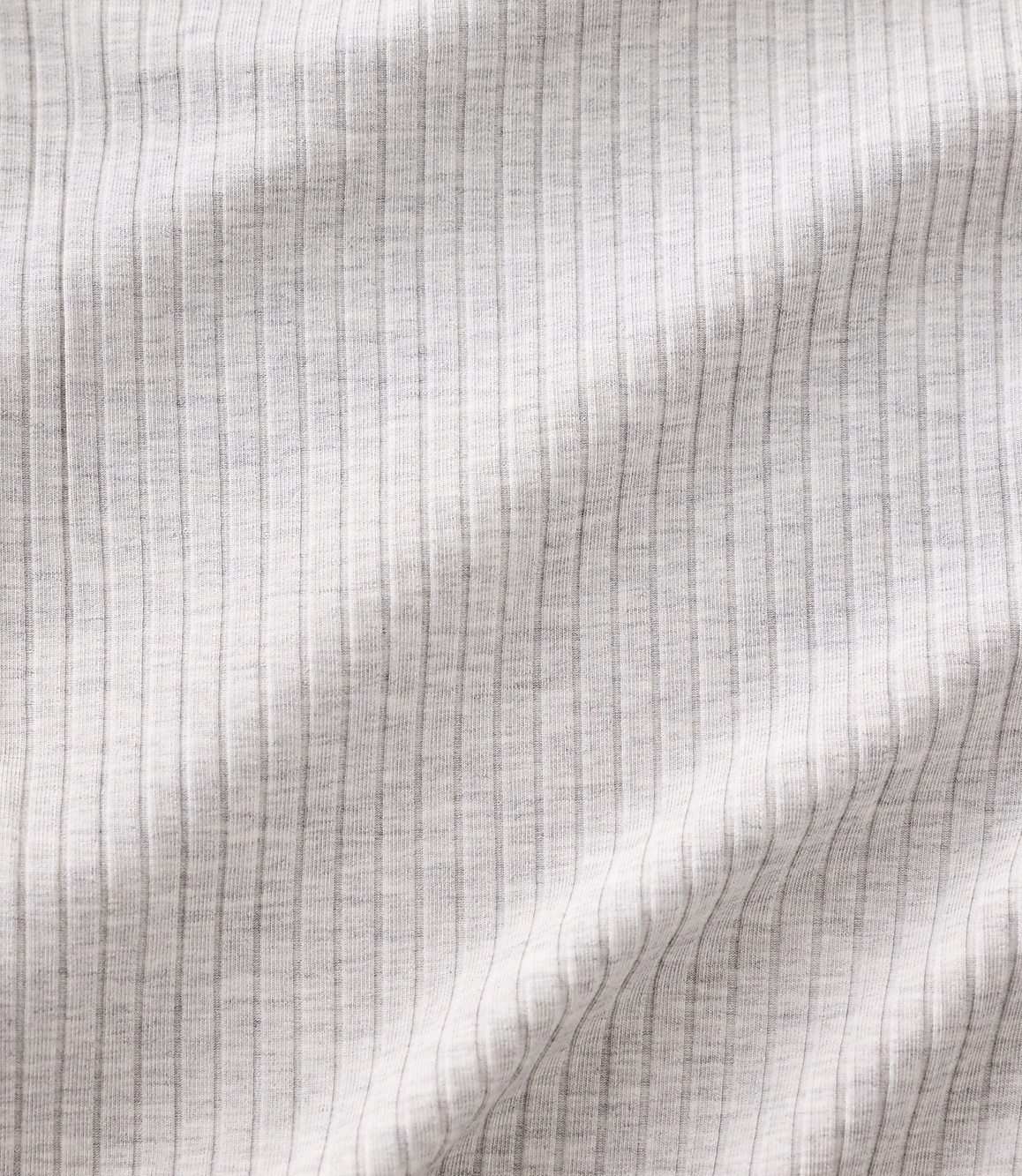 White ribbed fabric with soft folds and shadows fills the entire frame.