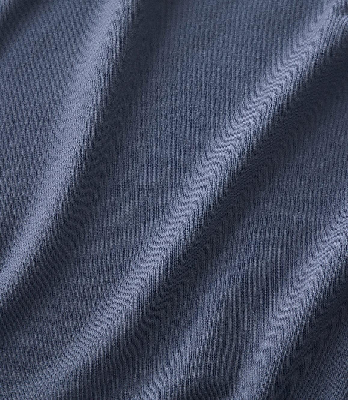 Soft, draped folds of blue-grey fabric fill the foreground and extend into the background.
