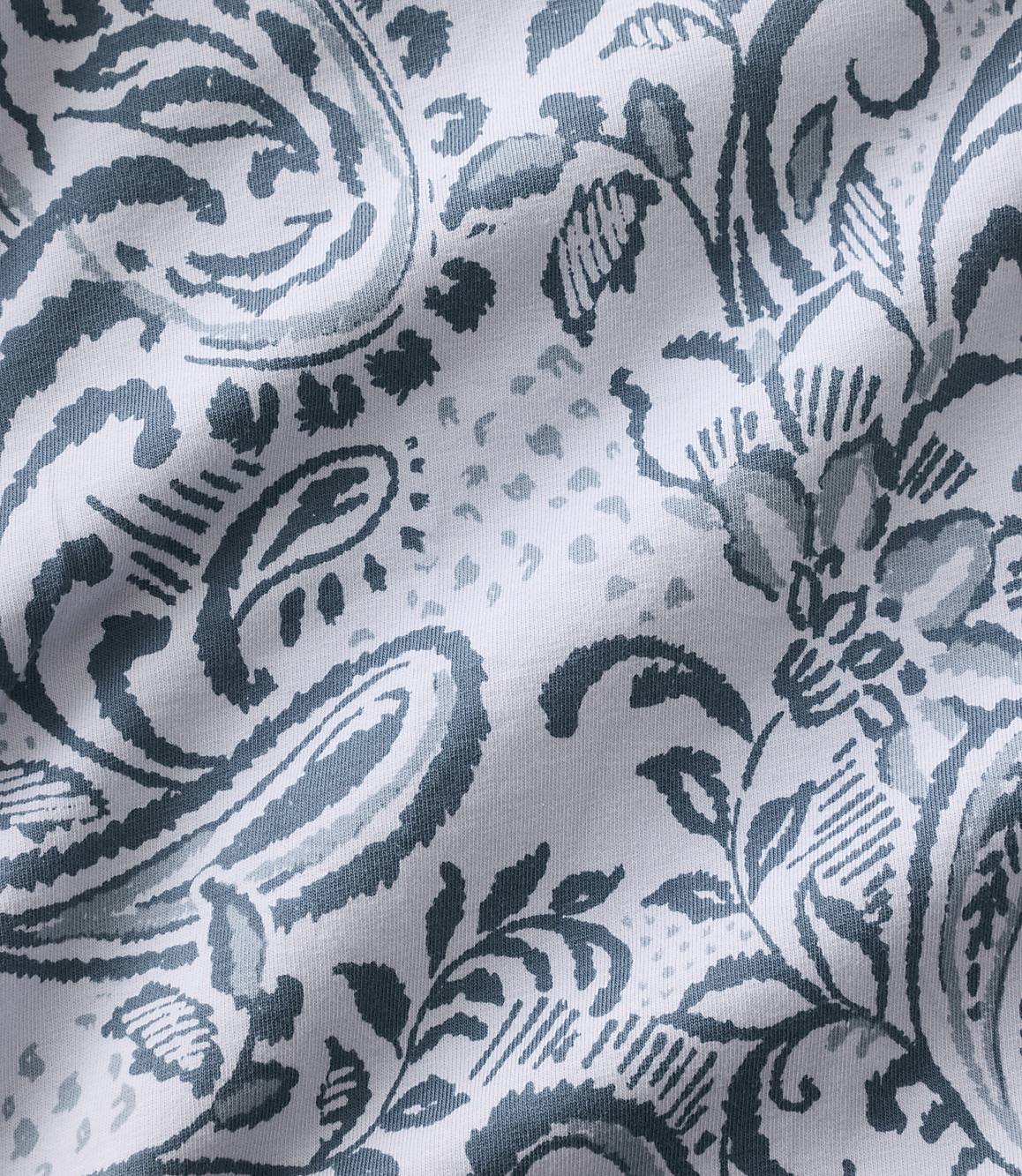 Blue and grey paisley and floral patterns are printed across a white, wrinkled fabric background.
