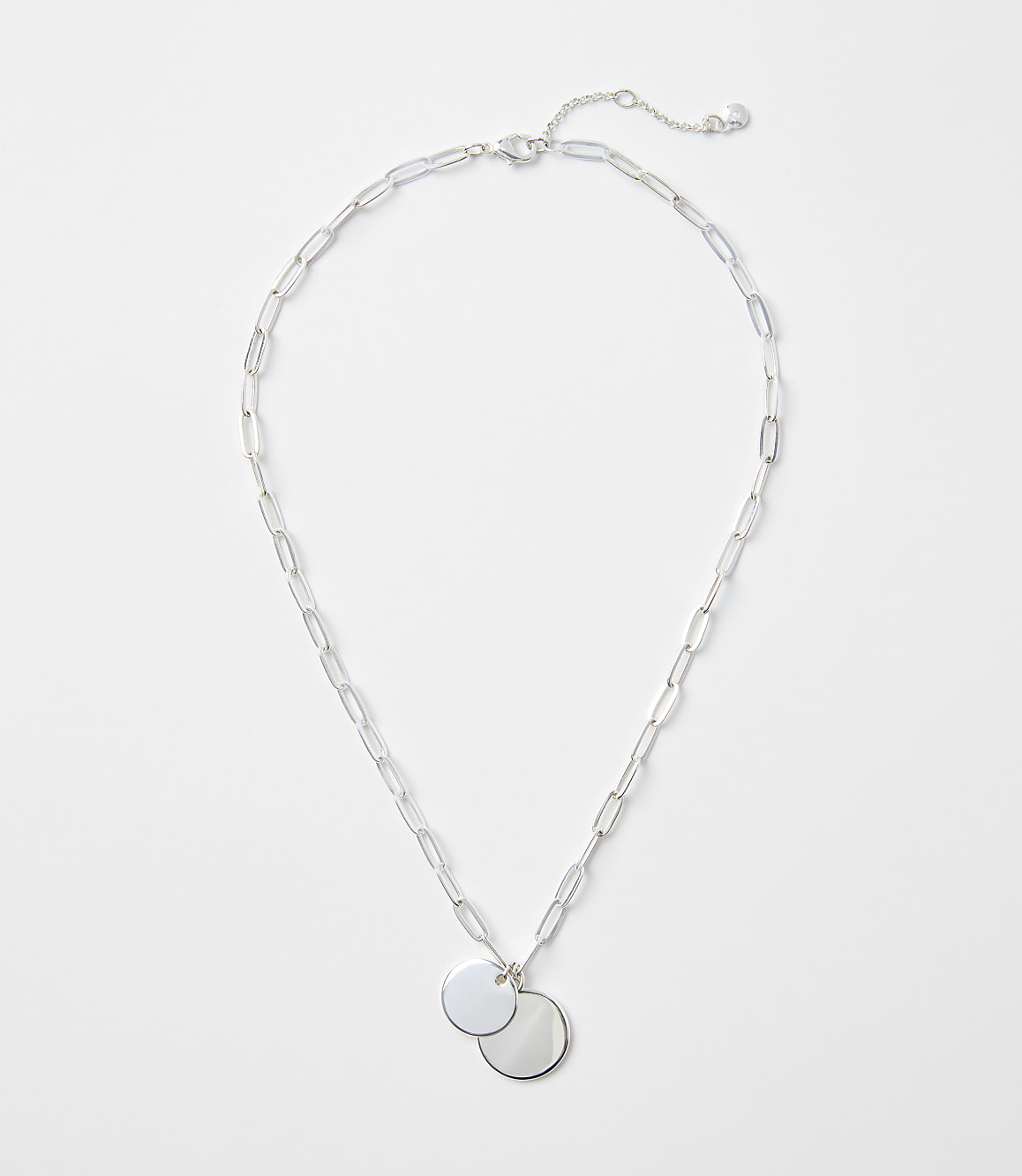 A silver chain necklace with two circular pendants rests on a plain white background.