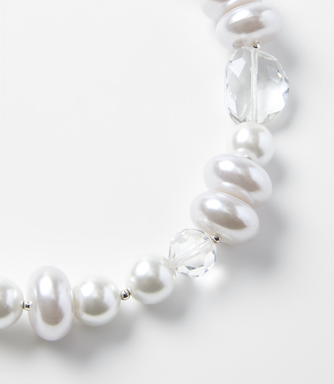 A string of white pearls and clear faceted crystals curves across a plain white background.
