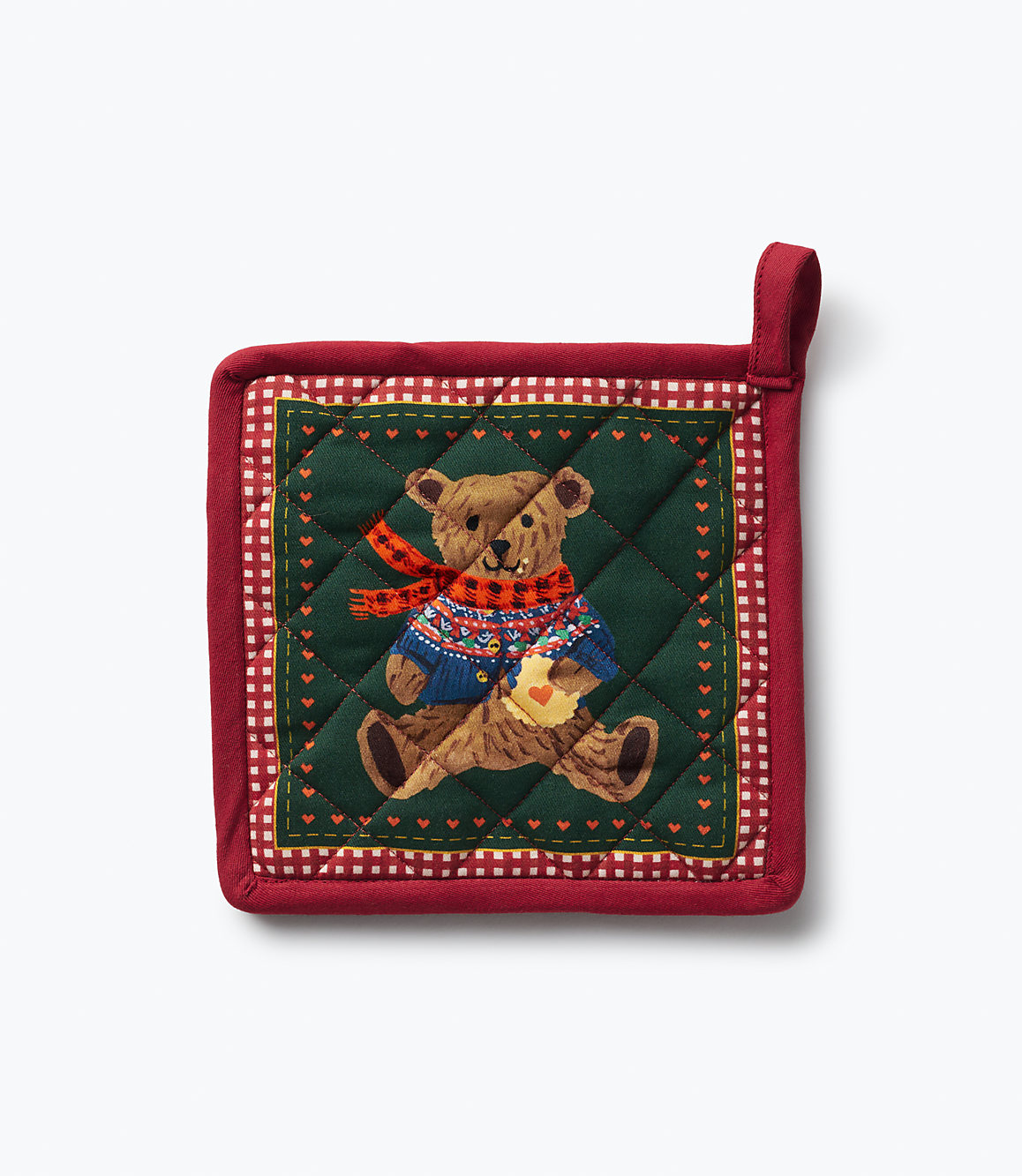 A red quilted pot holder featuring a teddy bear in a sweater and scarf sits against a plain white background.