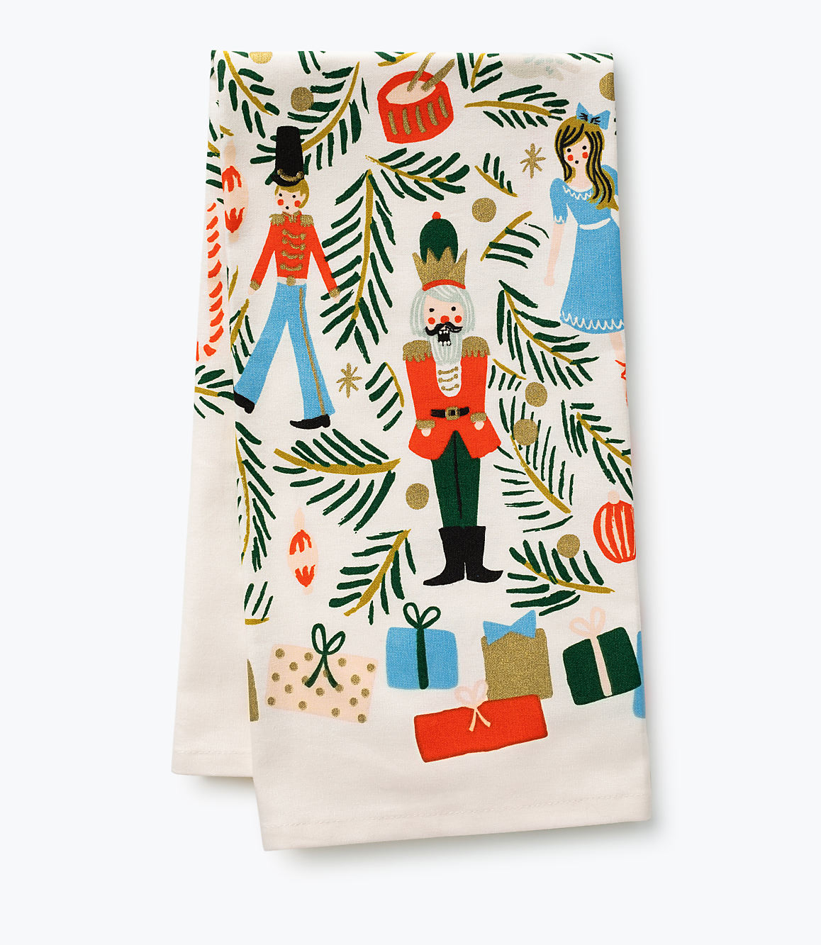 Nutcrackers, a doll, and wrapped gifts are scattered across a white fabric background adorned with green pine branches and gold ornaments.