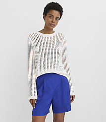 A woman in a white open-knit sweater and blue shorts stands against a plain white background. carousel Product Image 1